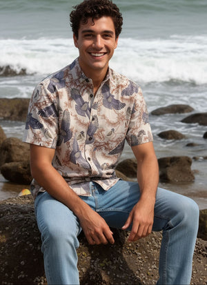 Man sitting on rocks by the ocean with mountains in the background