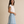 A woman modeling a light blue and white patterned tiered maxi skirt with a white short-sleeve top, standing against a neutral beige studio backdrop.