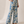 A woman modeling a blue and cream floral short-sleeve wrap top and matching wide-leg pants set, standing against a neutral beige studio backdrop.