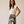 A woman modeling a cream short-sleeve top and a black maxi skirt with a large cream floral print, standing against a warm beige studio backdrop.