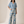 A woman modeling a matching blue floral top and wide-leg pants set against a warm beige studio backdrop.