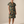 A woman modeling a short-sleeve button-front shirt dress with an abstract watercolor-style print in teal, olive green, tan, and brown tones, paired with brown leather sandals, against a plain beige studio background.