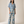 A woman modeling a matching two-piece set featuring a blue and beige floral print, consisting of a short-sleeve V-neck top and wide-leg trousers, set against a plain beige studio background.
