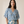 A woman modeling a matching two-piece set featuring a blue and beige floral print, consisting of a short-sleeve V-neck top and wide-leg trousers, set against a plain beige studio background.