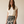 A woman modeling a cream short-sleeve top and a black midi skirt with a cream floral print, standing against a plain beige studio background.