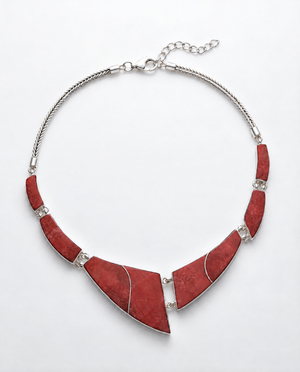 A statement bib necklace featuring large, angular red stone inlays set in silver-tone metal, connected by small clear rhinestones and suspended from a silver chain.