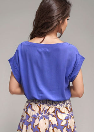 Woman wearing a blue top and floral skirt on a gray background