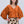 Woman wearing an orange top and patterned pants on a white background