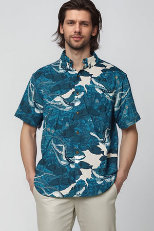 Man wearing a blue David Shepard patterned aloha shirt against a white background