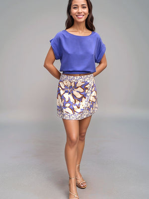 Woman wearing a blue top and patterned skirt on a gray background