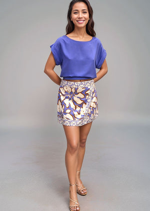 Woman wearing a blue top and patterned skirt on a gray background